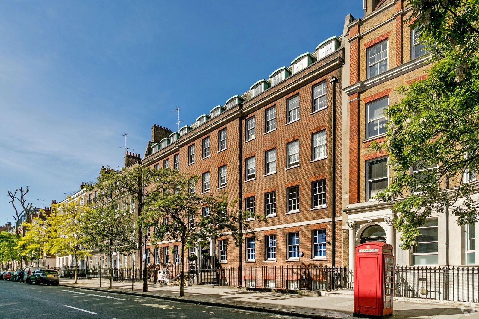 The new Artificial Societies London HQ — a red-brick Georgian terrace on a tree-lined street, with a red telephone box outside